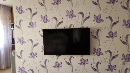 TV de pantalla plana en una pared con flores púrpuras en Ahtme apart, en Kohtla-Järve