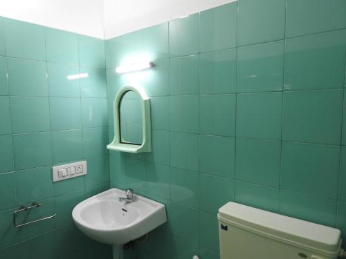 a bathroom with a sink and a toilet and a mirror at Kadalamma Beach Homestay in Alleppey