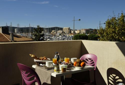 una mesa con comida y bebida en el balcón en Hôtel Baptistin, en Le Lavandou