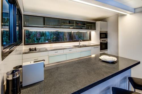 une cuisine avec des placards blancs et un comptoir dans l'établissement Waves 3 Luxury 3 Bedroom Endless Ocean Views Central Location + Buggy, à Île Hamilton