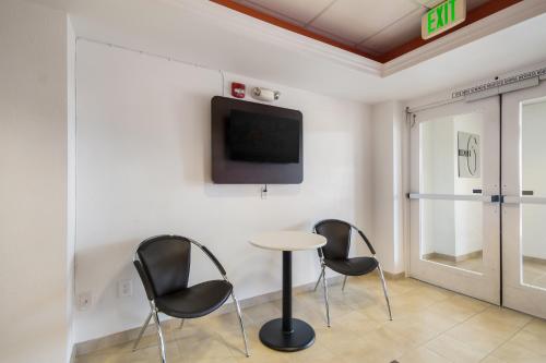 a room with three chairs and a table and a tv at Motel 6-Lemoore, CA in Lemoore