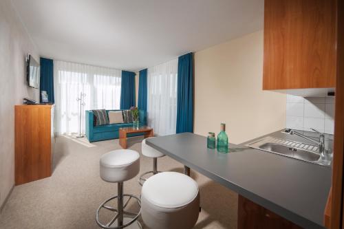 a kitchen with a counter and stools in a room at Victory Gästehaus Therme Erding in Erding
