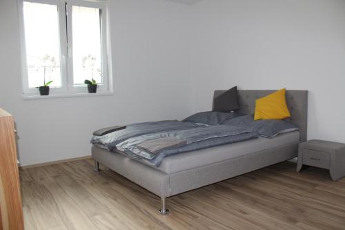 a bed in a room with white walls and windows at Apartment ANNO in Dunajská Streda