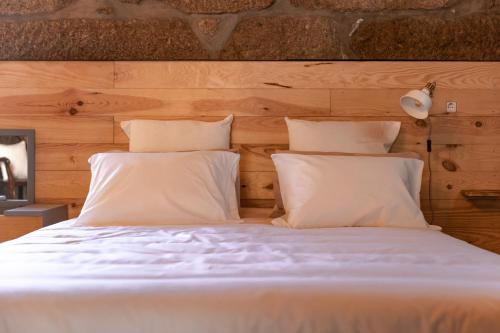 a bed with white sheets and pillows at A Casinha in Vila Nova de Famalicão