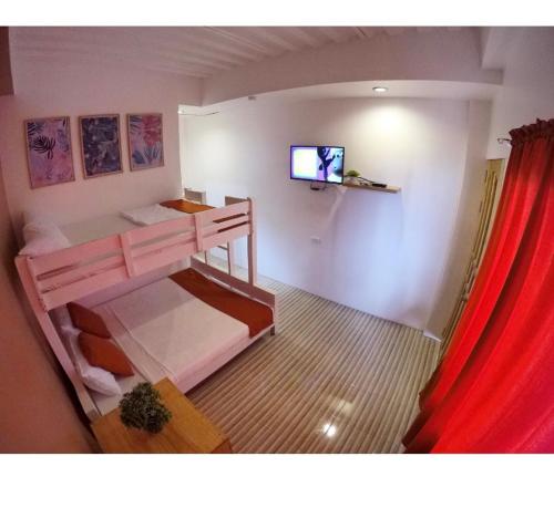 a bedroom with two bunk beds with a television in it at The BIGGIES Inn in Oslob