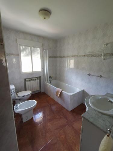 a bathroom with a tub and a toilet and a sink at Apartamentos Rascafria Cerquilla in Rascafría