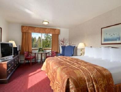 a hotel room with a bed and a tv and a table at Travelodge by Wyndham Juneau in Mendenhaven