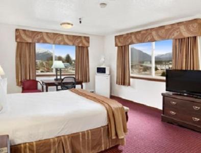 a hotel room with a bed and a flat screen tv at Travelodge by Wyndham Juneau in Mendenhaven