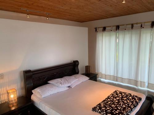 a bedroom with a bed with white sheets and a window at Hostal Hilltop Capurgana in Capurganá