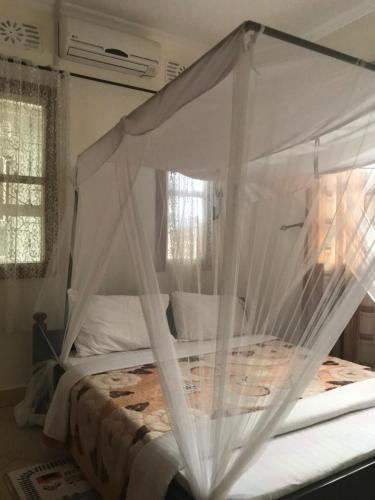 a bedroom with a canopy bed with white curtains at Le Parlour in Boma la Ngombe