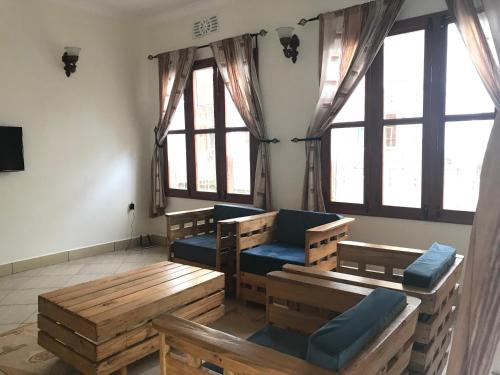 a living room with wooden benches and windows at Le Parlour in Boma la Ngombe