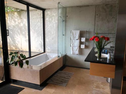 a bathroom with a tub and a vase of flowers at Snooze in Hout Bay Self-Catering in Hout Bay