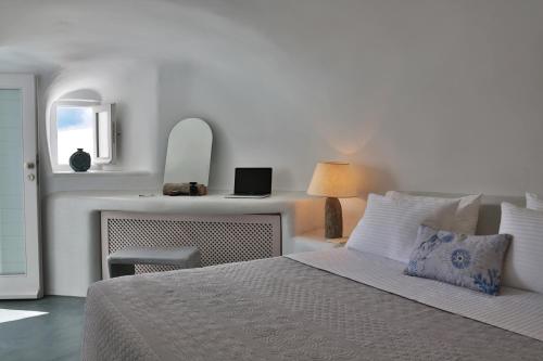a bedroom with a bed and a desk with a laptop at Lava Caves in Oia