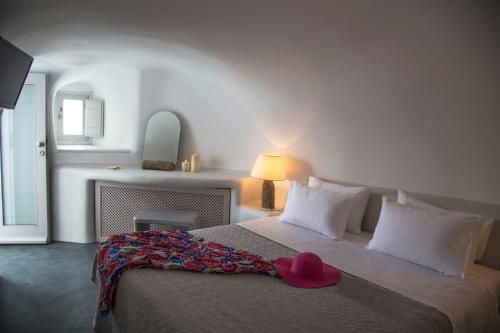 Un dormitorio con una cama con un sombrero rosa. en Lava Caves, en Oia