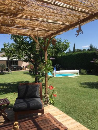a chair under a wooden pergola in a yard at Les Tignoliers in Tignieu-Jameyzieu