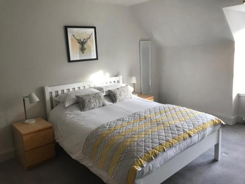 Dormitorio con cama blanca con manta amarilla y gris en Fantastic central location, en Inverness