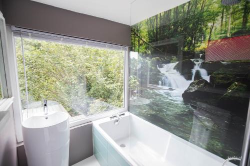La salle de bains est pourvue d'une fenêtre, d'une baignoire et d'un lavabo. dans l'établissement L'Xpérience, à Valgorge