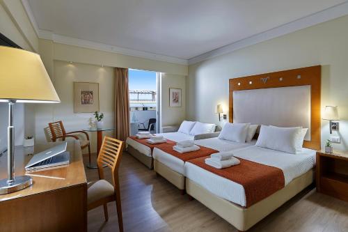 a hotel room with two beds and a desk at Atrion Hotel in Heraklio