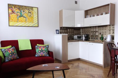 a living room with a red couch and a kitchen at Krakowskie Przedmieście "Night and Day" in Warsaw