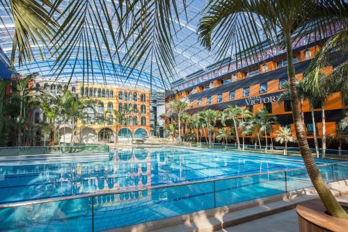 een groot zwembad in een hotel met een glazen plafond bij Hotel Victory Therme Erding in Erding