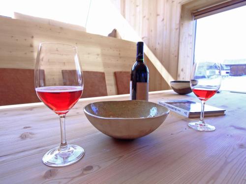 Ufogel في Nußdorf: كأسين من النبيذ وزجاجة من النبيذ على طاولة خشبية