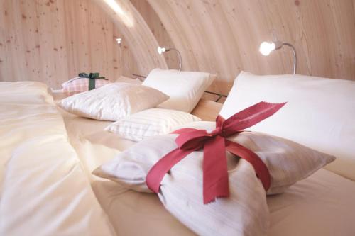 łóżko z białymi poduszkami z czerwoną wstążką w obiekcie Ufogel w mieście Nußdorf