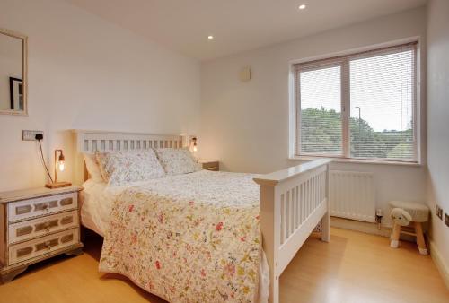 a white bedroom with a bed and a window at Beautiful duplex penthouse - roof garden, views, parking in Newcastle upon Tyne