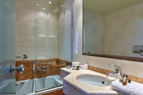 a bathroom with a tub and a sink and a shower at Atrion Hotel in Heraklio