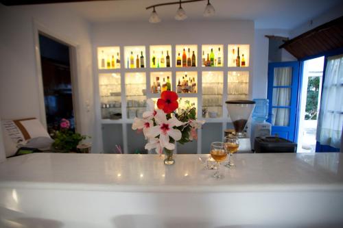 a white counter with a vase of flowers and glasses at Naxian Queen Luxury Villas & Suites in Agia Anna Naxos