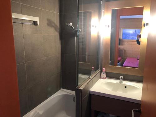 a bathroom with a tub and a sink and a mirror at Appartement cozy centre Alpe d'Huez in L'Alpe-d'Huez