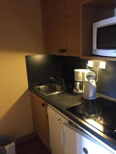 une petite cuisine avec un évier et un micro-ondes dans l'établissement Appartement cozy centre Alpe d'Huez, à L'Alpe-d'Huez