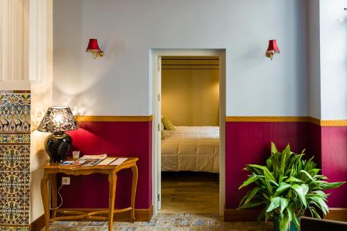 a room with a bed and a table with a lamp at Hospedium Hotel El Nido de Alcudia Suites in Almodóvar del Campo