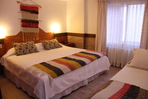 a bedroom with a bed with a colorful blanket on it at Hotel Rucaitue in Osorno