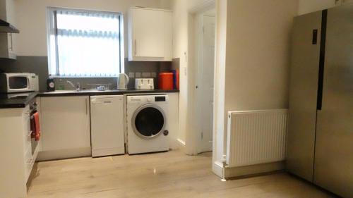 a kitchen with a washing machine and a sink at Grand Airport Ensuites in Harmondsworth