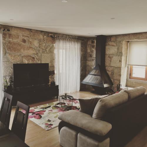 a living room with a couch and a tv at Isabel do Couto - casa de charme in Castro Daire