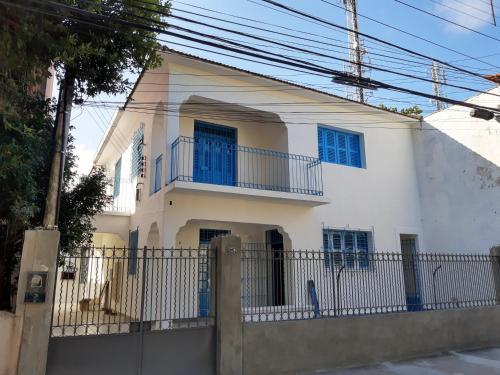 a white house with blue windows and a fence at Zili Pernambuco - Hostel Pousada in Recife