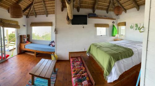 a bedroom with a bed and a bench and a tv at Cabañas Punta Papaya in Punta Del Diablo