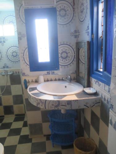 een blauwe en witte badkamer met een wastafel en een raam bij La Maison Bleue in Sidi Ifni
