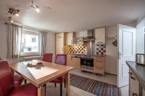 AlpenLiving في مايرهوفن: مطبخ مع طاولة خشبية وكراسي حمراء