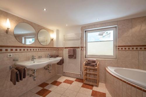 a bathroom with a sink and a tub and a window at AlpenLiving in Mayrhofen