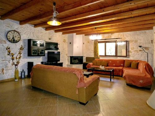 a living room with couches and a stone wall at Rouveli Villa with private garden and barbeque in Tragaki