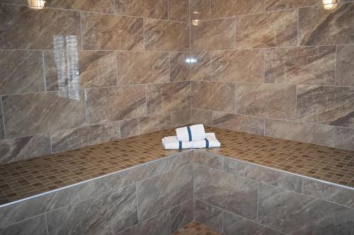 y baño con ducha de azulejos y 2 toallas plegables. en Americas Best Value Inn Manteca, en Manteca