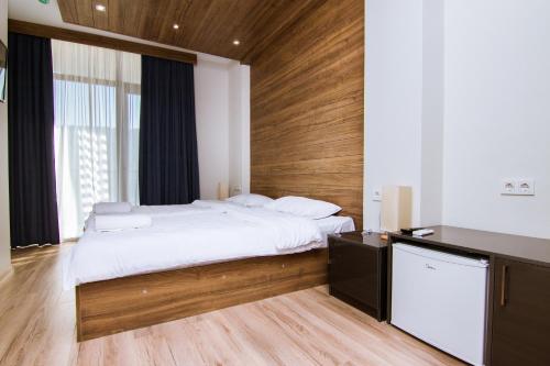 a bedroom with a large bed with a wooden wall at Victoria Inn Tbilisi in Tbilisi City