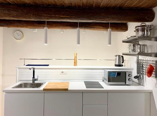 Una cocina blanca con fregadero y microondas. en SECRET ROOM NAPLES historic center, en Nápoles