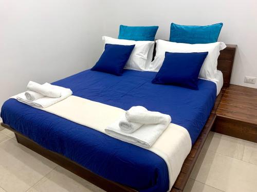 a blue and white bed with blue pillows and towels at SECRET ROOM NAPLES historic center in Naples