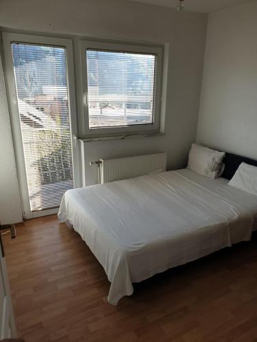 a white bed in a room with two windows at Villa Fruit Garden in Sarajevo