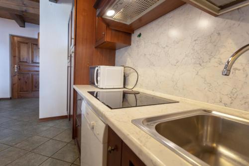 a kitchen with a sink and a microwave at Chalet Mew in La Thuile