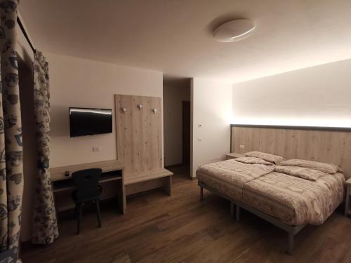 um quarto com uma cama, uma secretária e uma televisão em All'Amicizia em Santo Stefano di Cadore