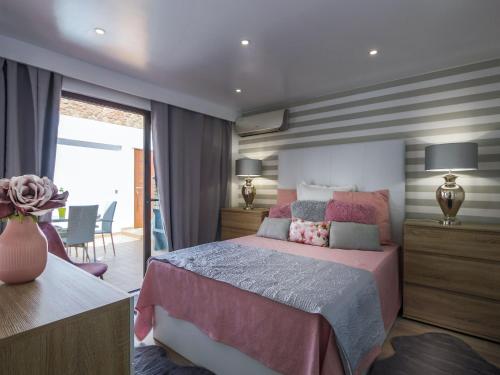 a bedroom with a pink bed and a dining room at Luxury Apartment, 3 min Walk to Beach, Albufeira in Guia