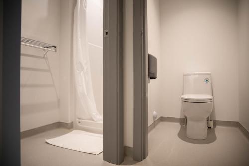 La salle de bains blanche est pourvue d'une douche et de toilettes. dans l'établissement HI Jasper - Hostel, à Jasper